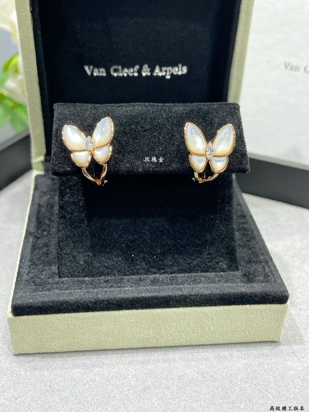 Butterfly stud earrings with white mother-of-pearl petals and gold-tone details on display box