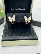 Butterfly stud earrings with white mother-of-pearl petals and gold-tone details on display box