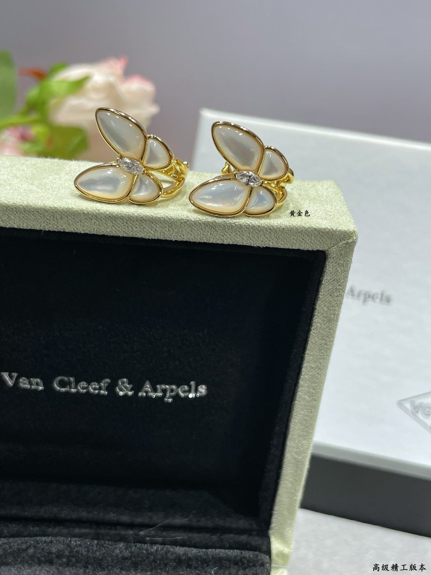 Butterfly stud earrings with white mother-of-pearl petals and gold-tone prongs on box