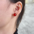 Gold-tone stud earrings with red round cabochon on the ear