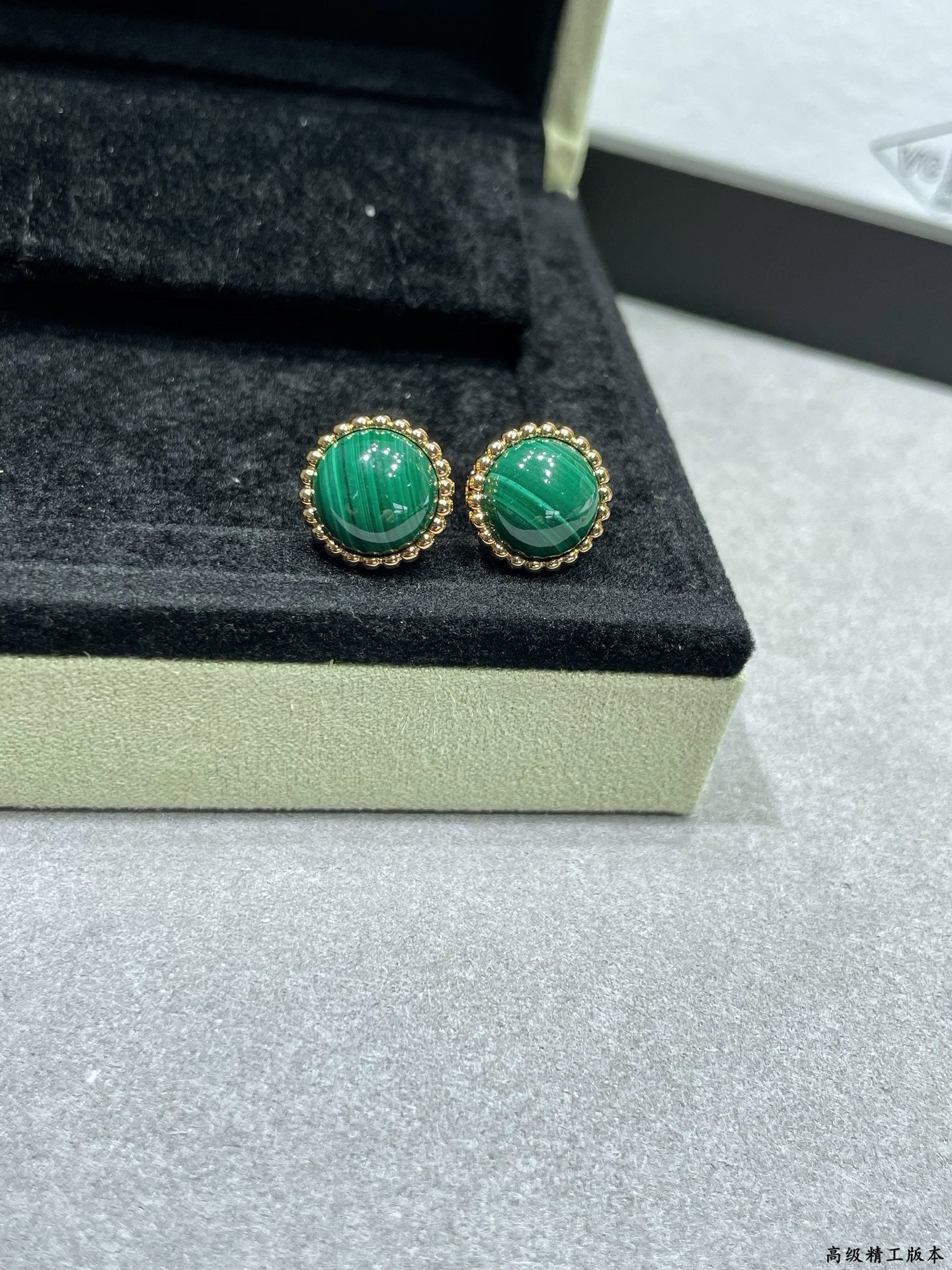 Van Cleef & Arpels earrings, gold-tone studs with green round stones on display