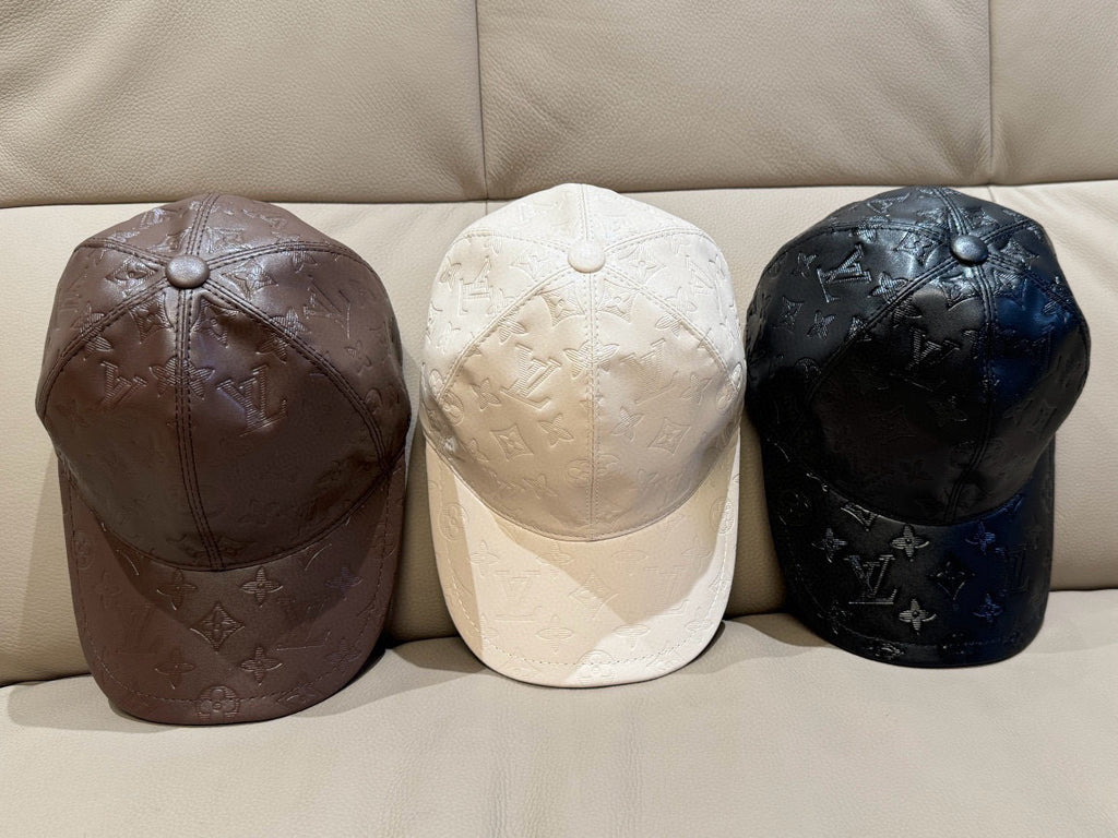 Three Louis Vuitton caps: dark brown, white, and black embossed monogram