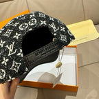 Black monogram-pattern cap with adjustable strap and hanging tag at the back