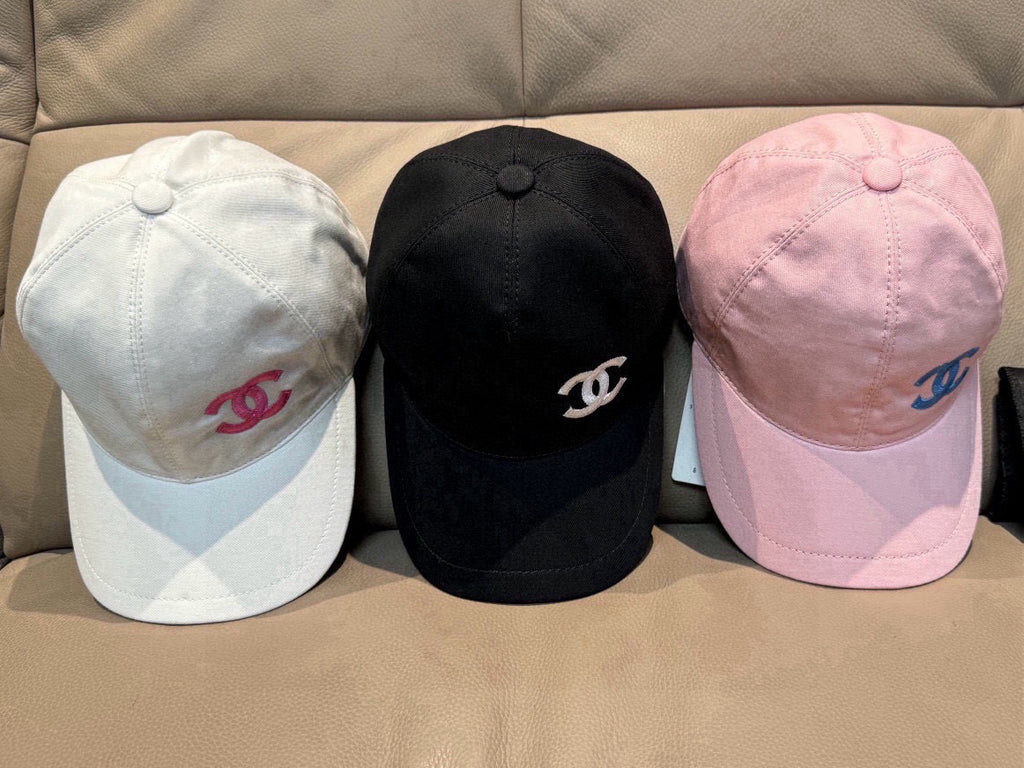 Three baseball caps: white, black, and pink with Chanel logo emblems.