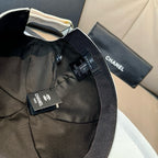 Black baseball cap with Chanel tags and adjustable strap, curved brim.