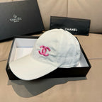 White baseball cap with pink Chanel logo on front panel, curved brim.