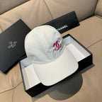 White baseball cap with pink Chanel logo, curved brim and stitched panels.