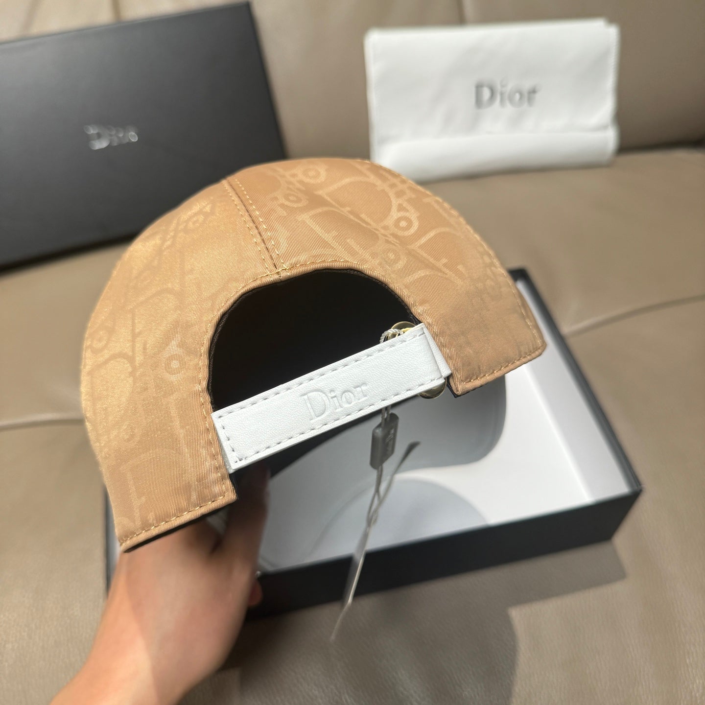 Dior cap back with tan monogram crown and white strap, adjustable buckle.