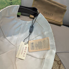 Gucci baseball cap in white with black strap and hanging tags on the inside