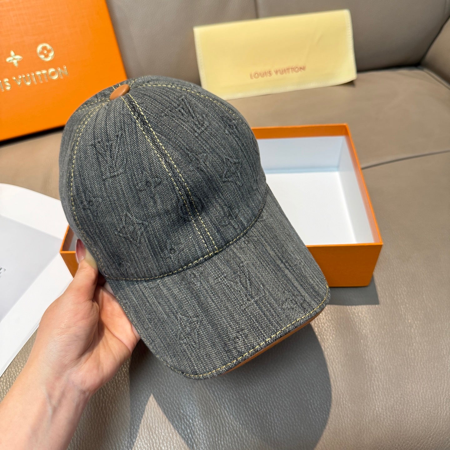 Louis Vuitton denim cap shown from side, dark blue-gray with LV stitching details