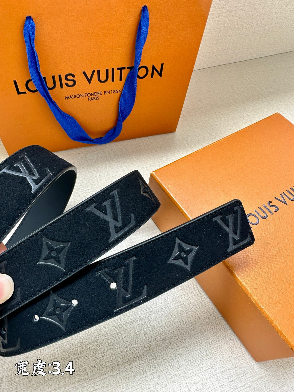 Dark blue belt with monogram motifs and silver-tone buckle, laid flat