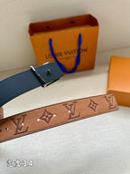 Monogram leather belt strap with gold-tone accents, set beside a blue leather belt piece