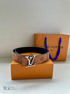 Tan/brown monogram belt with gold-tone V buckle and dark backing, laid on boxes