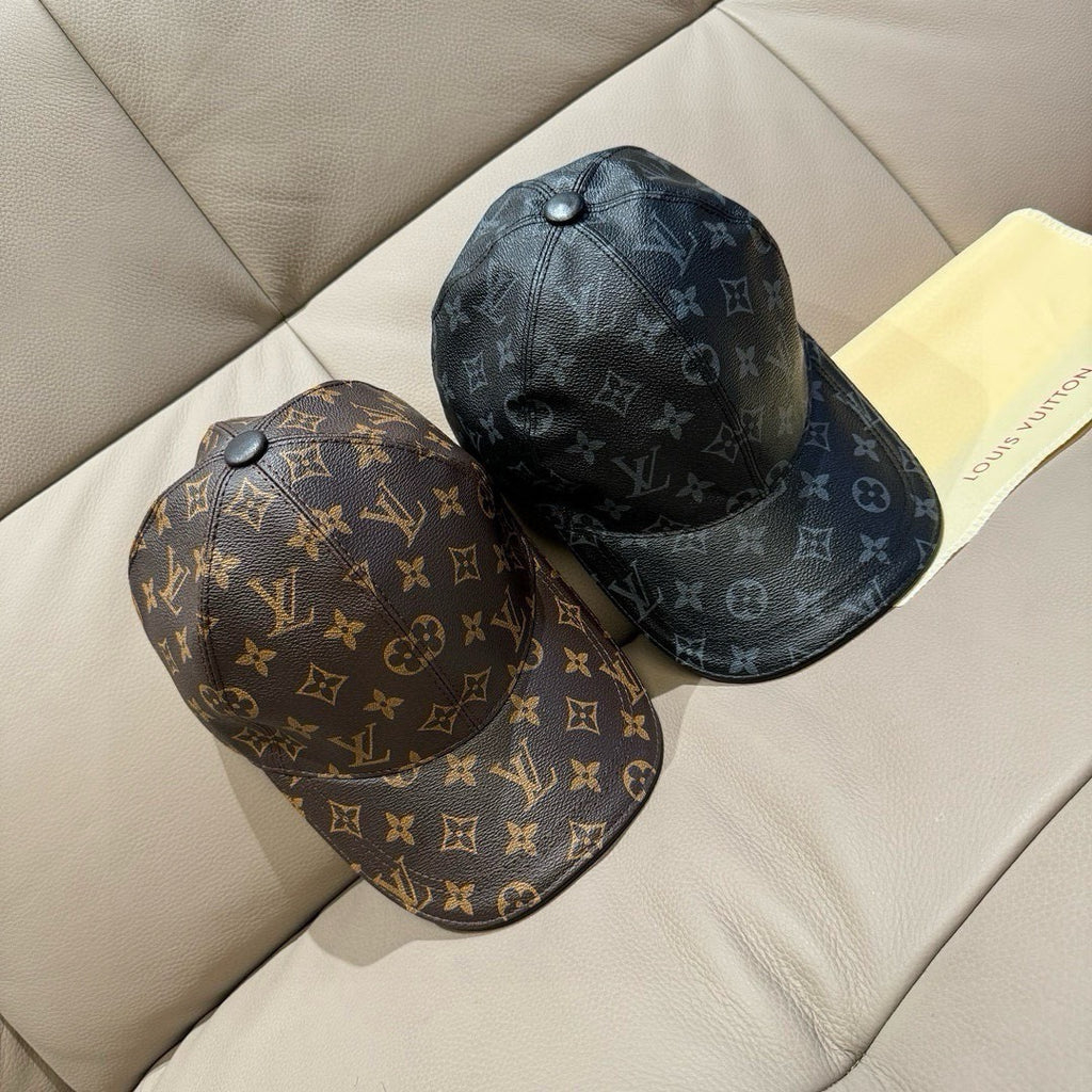 Two Louis Vuitton monogram baseball caps, dark and brown, on couch