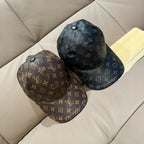 Two Louis Vuitton monogram baseball caps, dark and brown, on couch