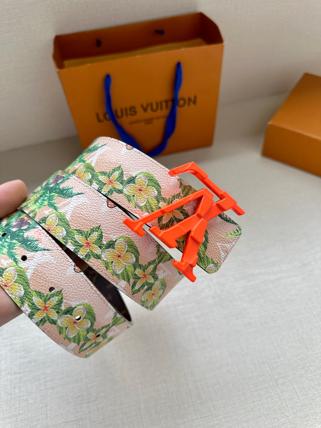 Louis Vuitton belt: floral strap detail with orange buckle and visible stitching