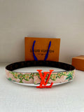 Louis Vuitton belt with floral strap and orange LV buckle on dark backing