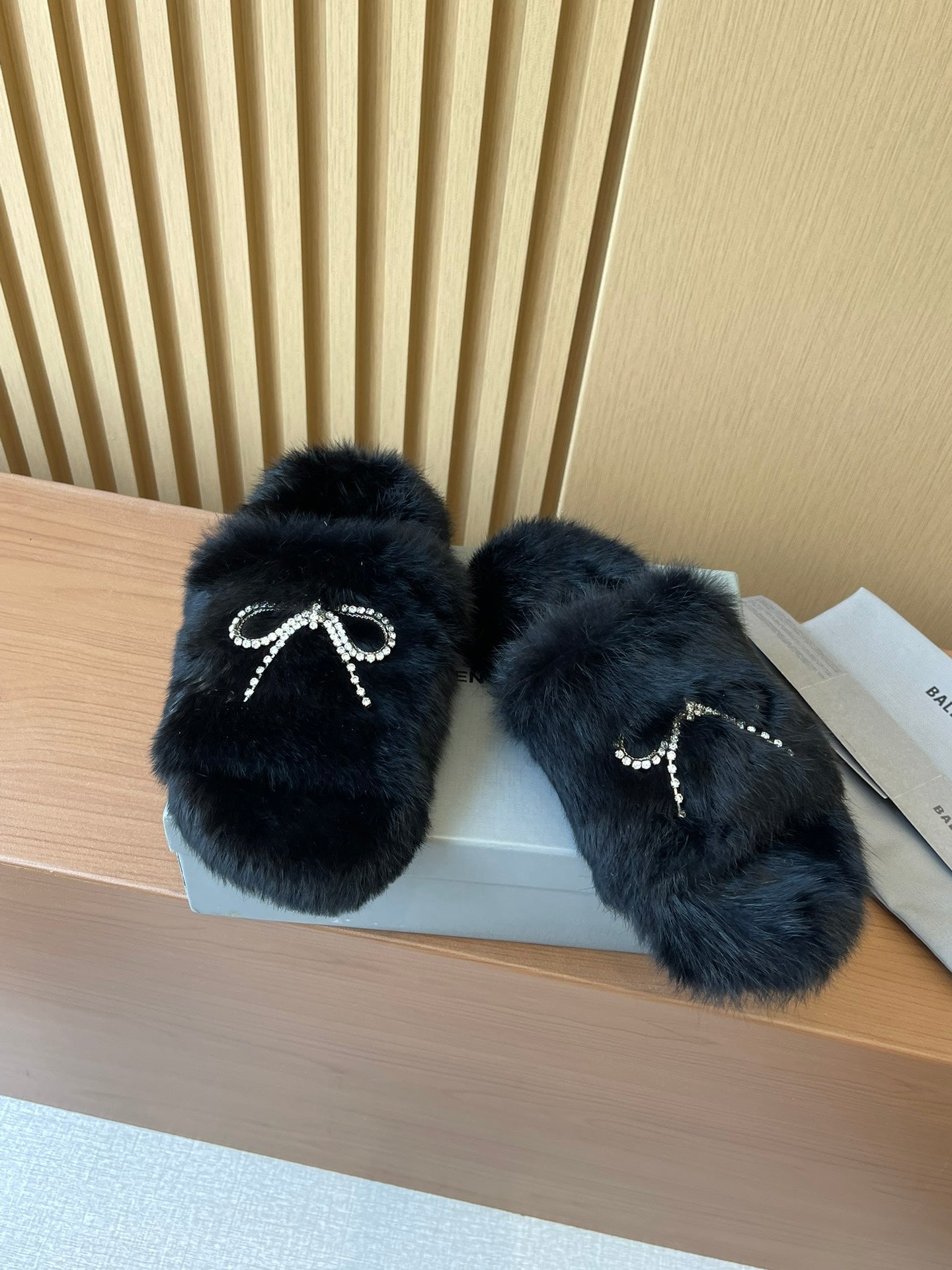 Balenciaga fuzzy sandals with dark fur texture and crystal bow accents