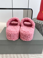 Pink fuzzy open-toe slide sandals with curved red logo on straps