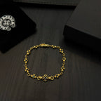Gold charm bracelet with blue flower beads on a dark wood surface.