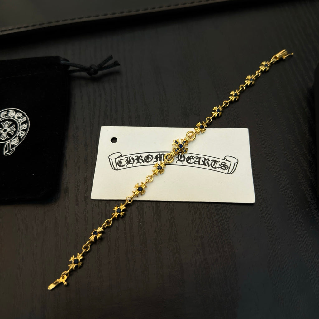 Gold charm bracelet with blue accents on a white product tag beside a box.