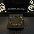Gold charm bracelet with blue flower beads, laid on a black gift box.