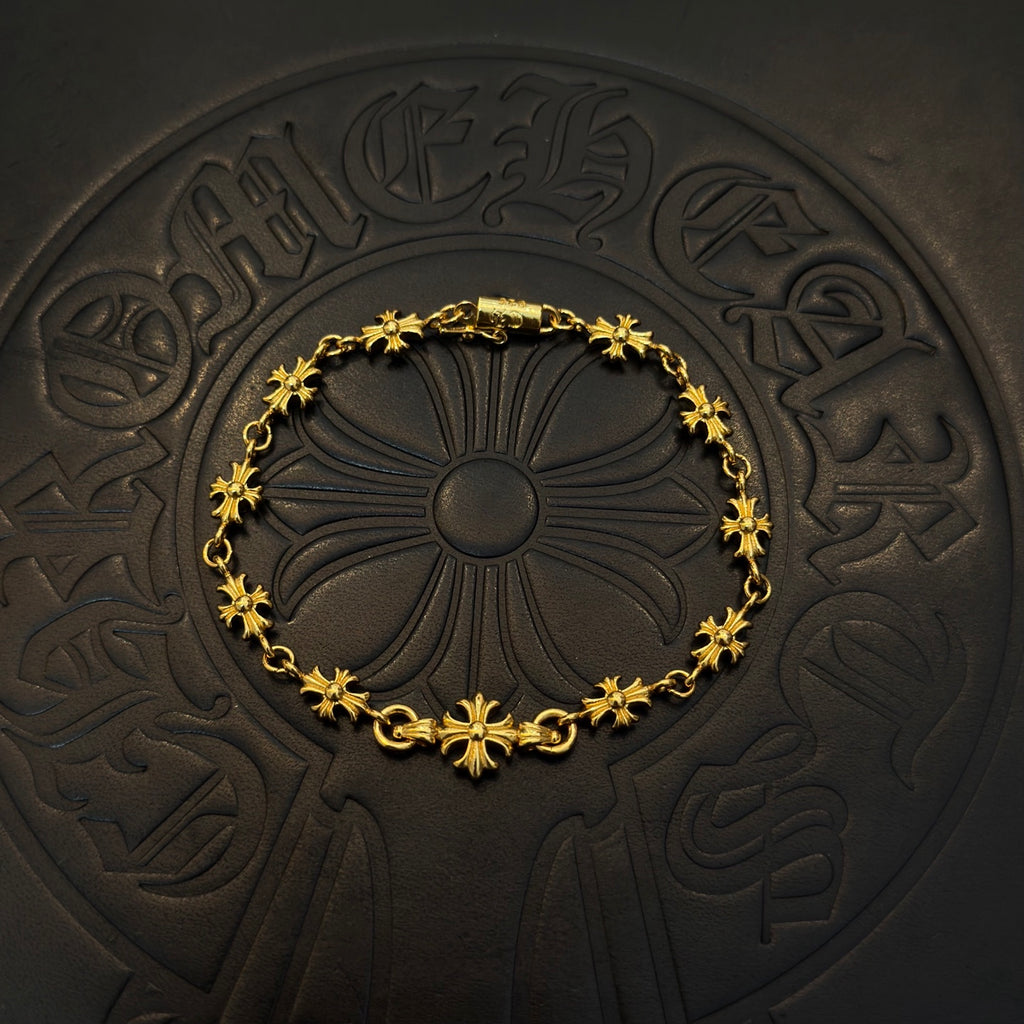 Gold charm bracelet with blue flower beads, centered on a dark embossed coaster.