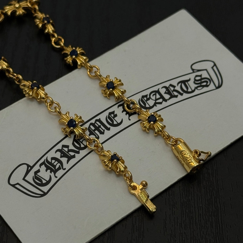 Gold charm bracelet with blue flower charms on a white product tag, close up.