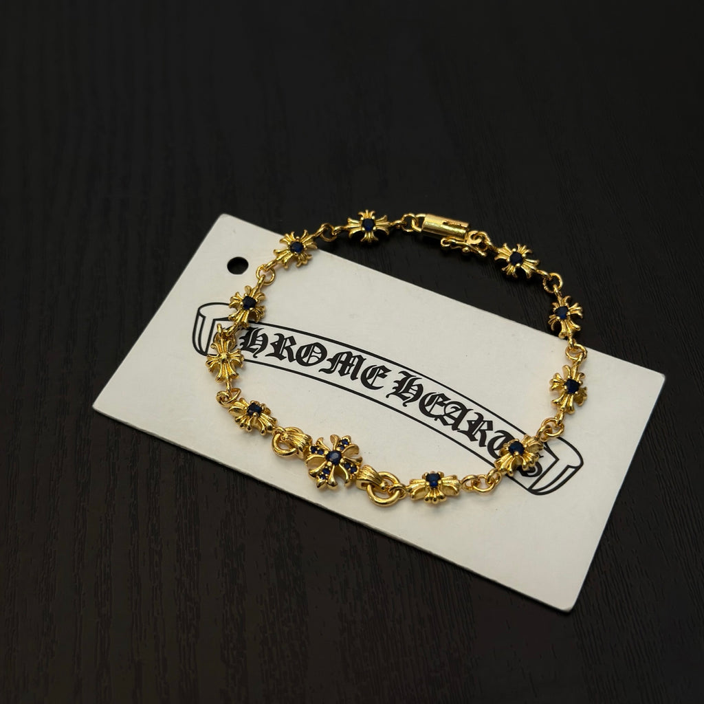 Gold charm bracelet with blue flower beads on a white product tag.