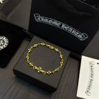 Gold-tone link bracelet with green flower charms on a black jewelry box