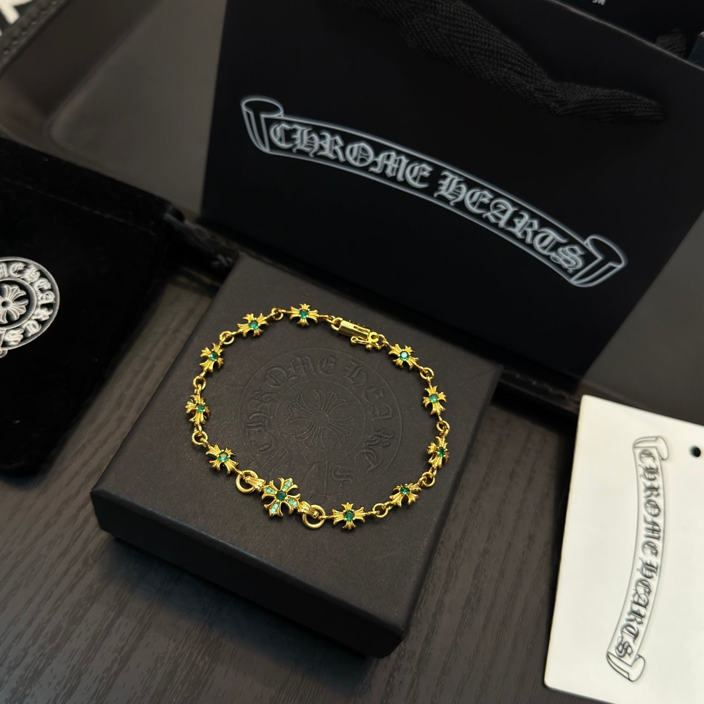 Gold-tone link bracelet with green flower charms on a black jewelry box