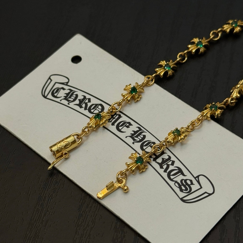 Gold-tone link bracelet close-up with green flower charms and cross accents
