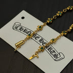 Gold-tone link bracelet close-up with green flower charms and cross accents