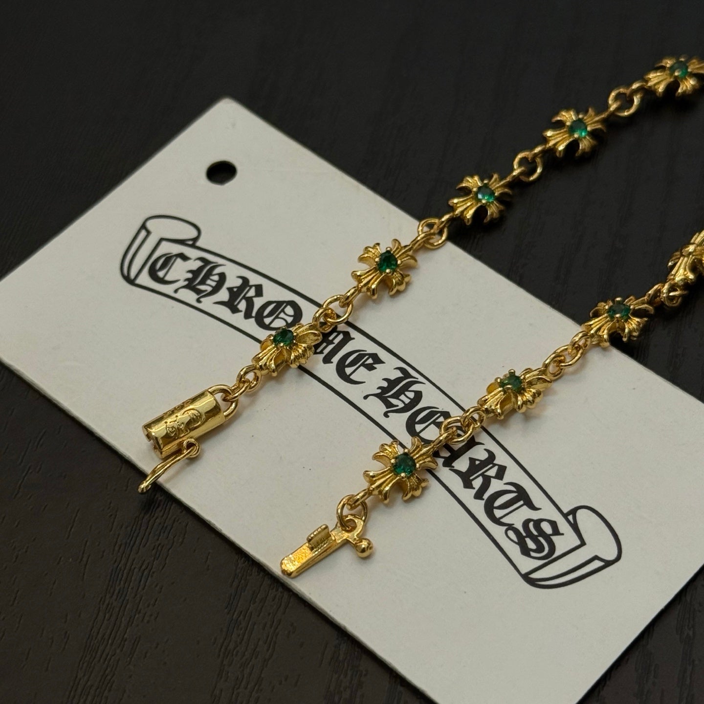 Gold-tone link bracelet close-up with green flower charms and cross accents