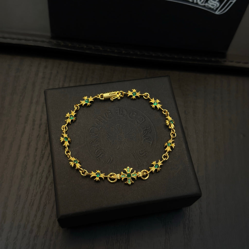 Gold-tone link bracelet with green flower charms on a black jewelry box