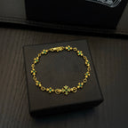 Gold-tone link bracelet with green flower charms on a black jewelry box