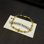 Gold-tone link bracelet with green flower charms on a white backing card