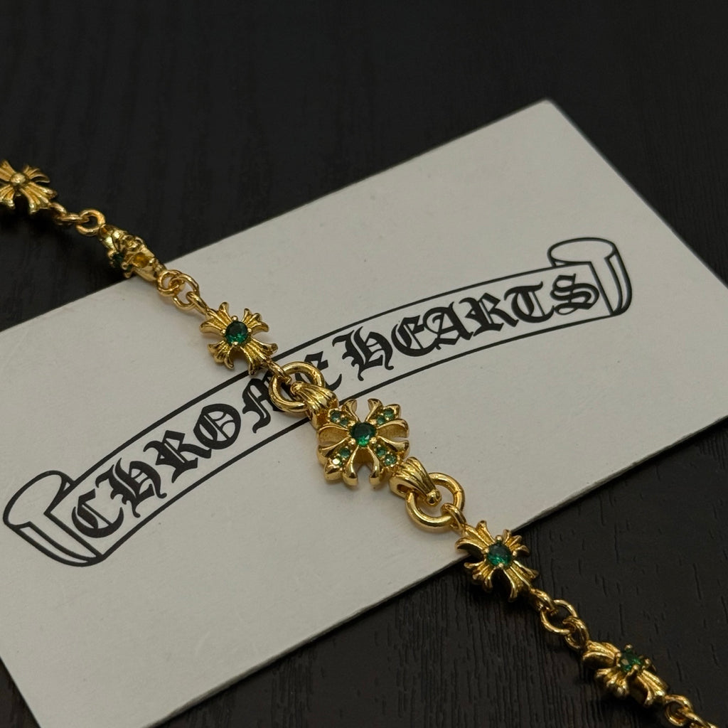 Gold-tone link bracelet close-up with green flower charms and small cross