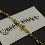 Gold-tone link bracelet close-up with green flower charms and small cross