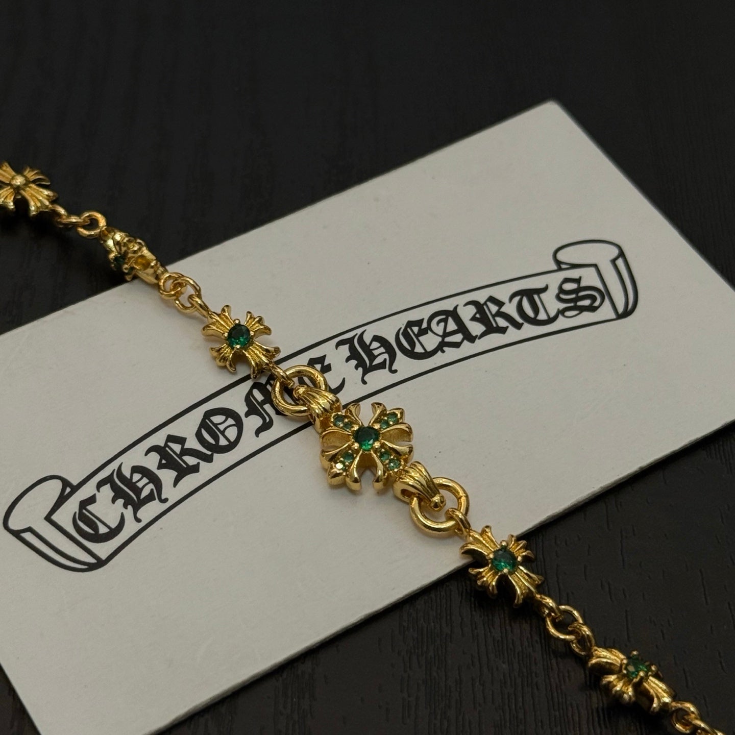 Gold-tone link bracelet close-up with green flower charms and small cross