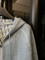 Light gray zip-up hoodie with hood seam detail and patterned lining at collar