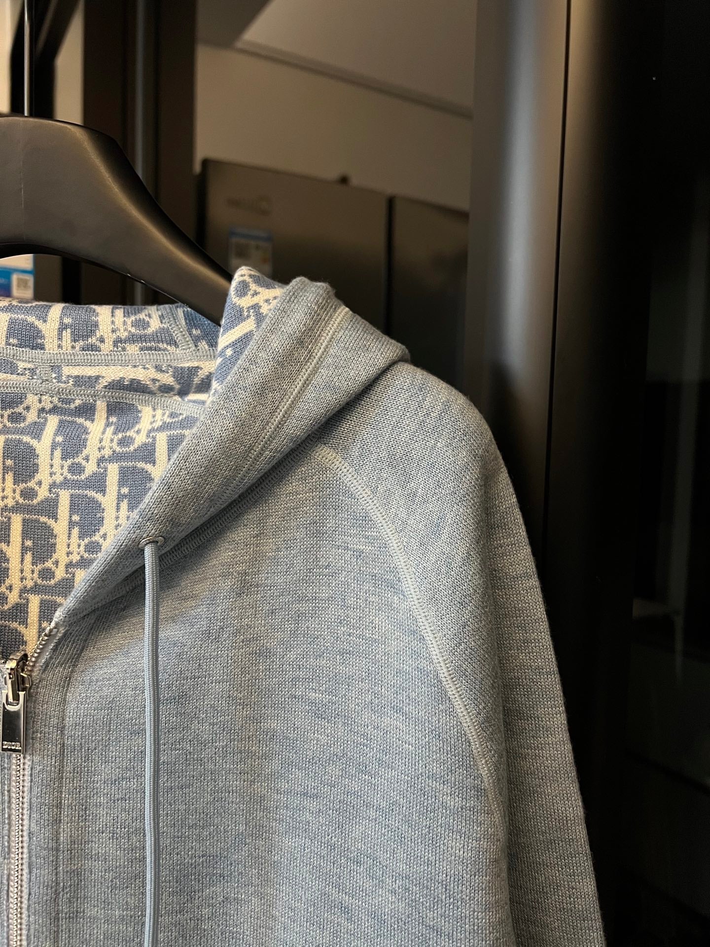 Light gray zip-up hoodie with hood seam detail and patterned lining at collar