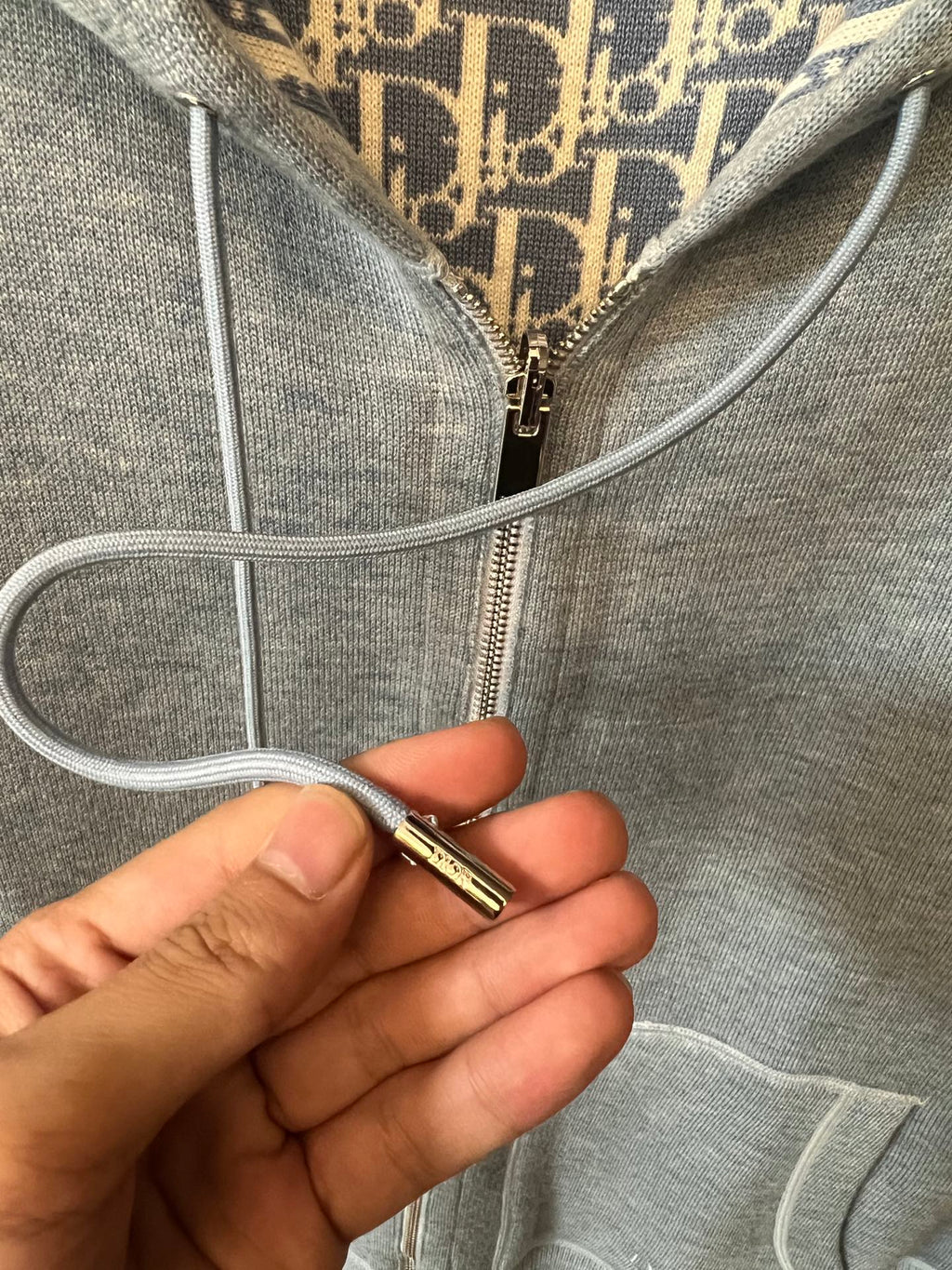 Light gray hoodie front zipper pull with corded hood drawstrings