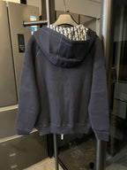 Navy zip-up hoodie with hood and front pockets, back view with monogram-lined hood.