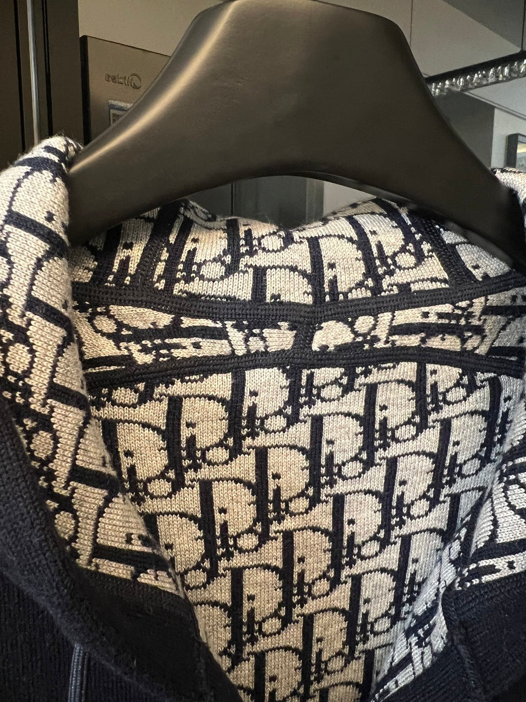 Dior monogram hood lining fabric with navy trim on a dark hoodie.