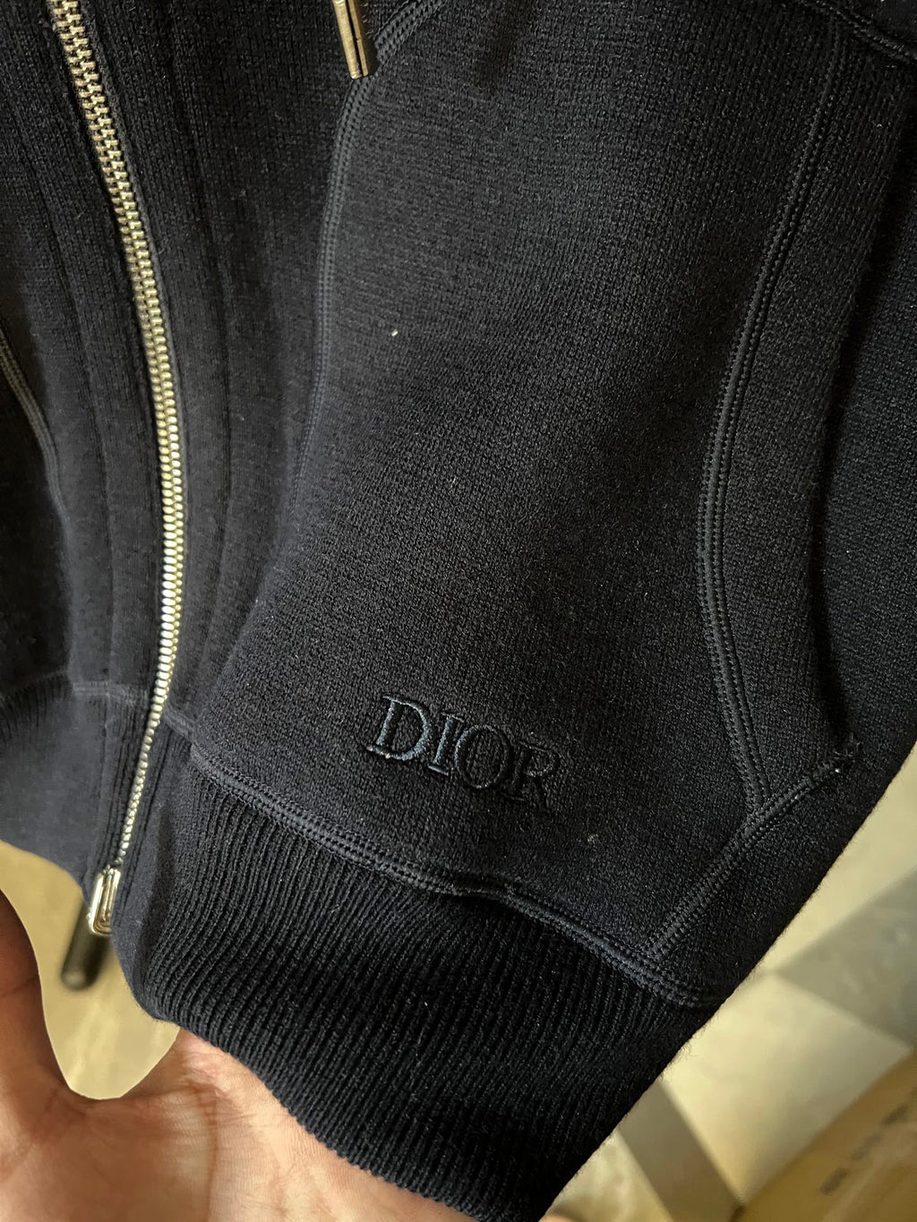 Dark hoodie hem with Dior logo on knit cuff and gold zipper trim.