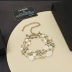 Charm bracelet with gold-tone links, white shell beads, pearls, and crystal accents