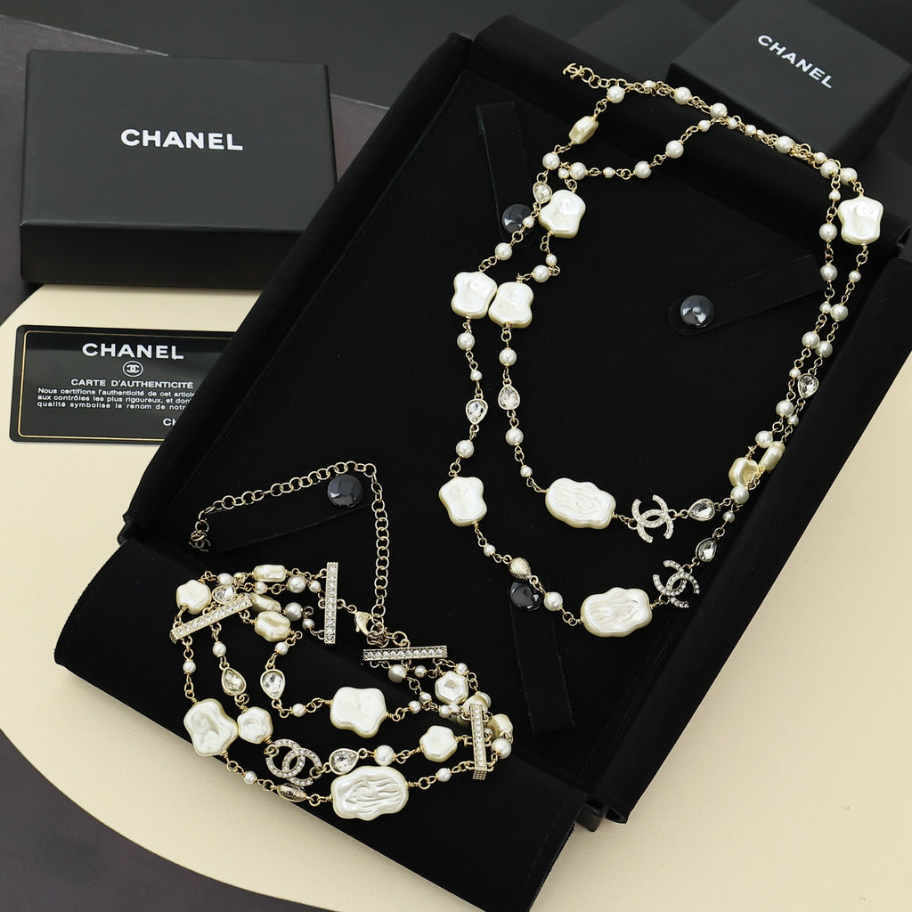 Pearl charm necklace with white shell flower charms on a black jewelry display tray