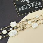 Gold-tone charm bracelet with white shell hearts, pearls, and an oval crystal center link