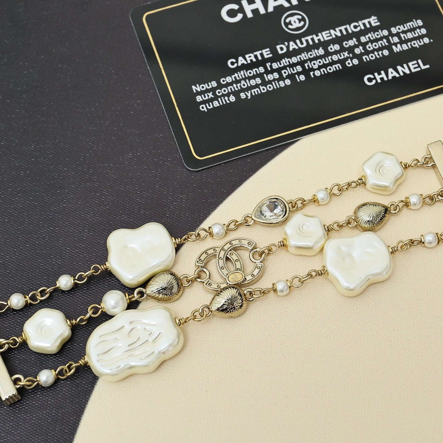 Gold-tone charm bracelet with white shell hearts, pearls, and an oval crystal center link